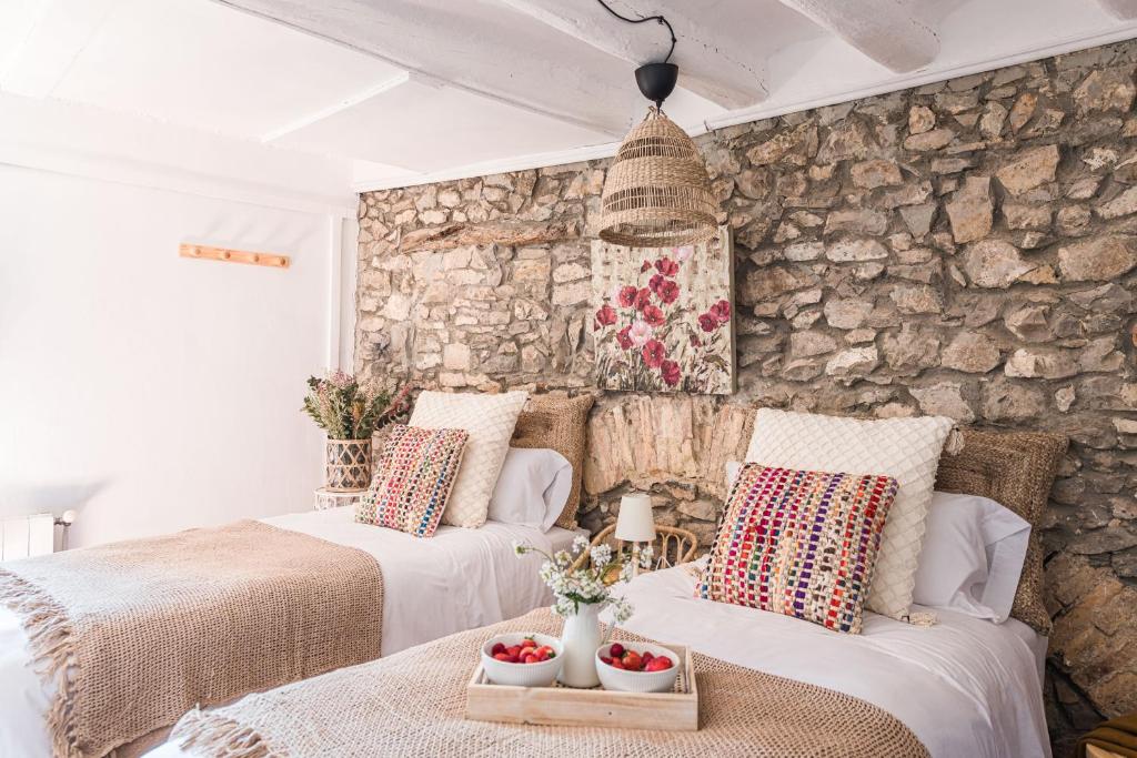 two beds in a room with a stone wall at Menta Rural in San Pedro Sallavinera