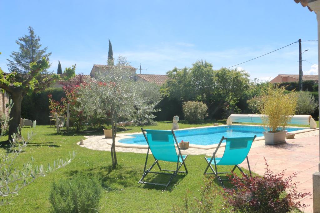 a yard with two chairs and a swimming pool at Un petit coin de Paradis in Mazan