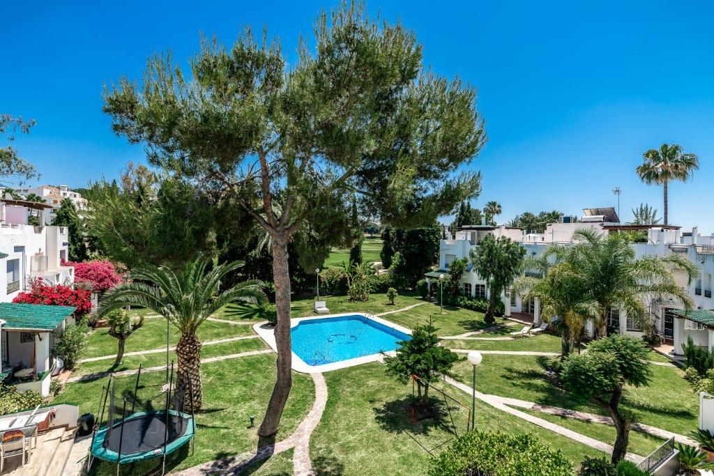 an apartment with a swimming pool and palm trees at Townhouse at Los Naranjos GC in Marbella