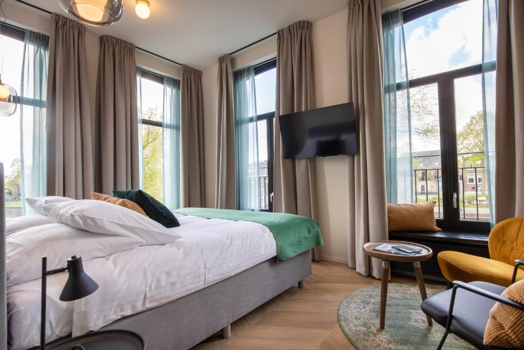 a bedroom with a bed and a tv and windows at Hotel van der Meer in Dokkum