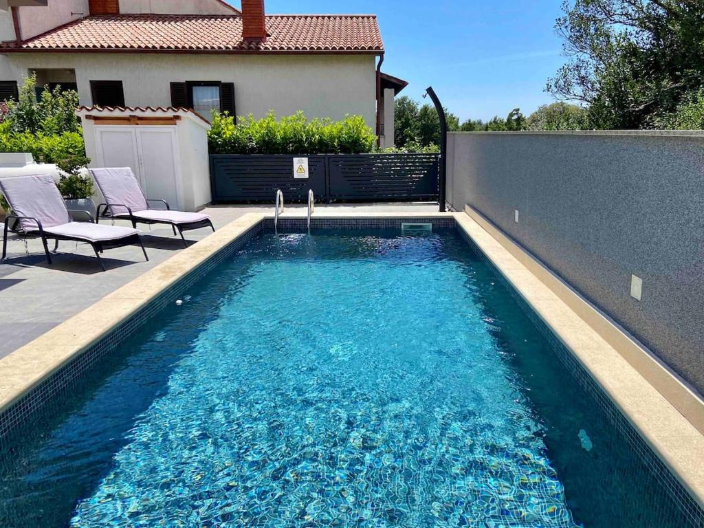 a swimming pool with two chairs next to a fence at Holiday house Veli vrh in Pula
