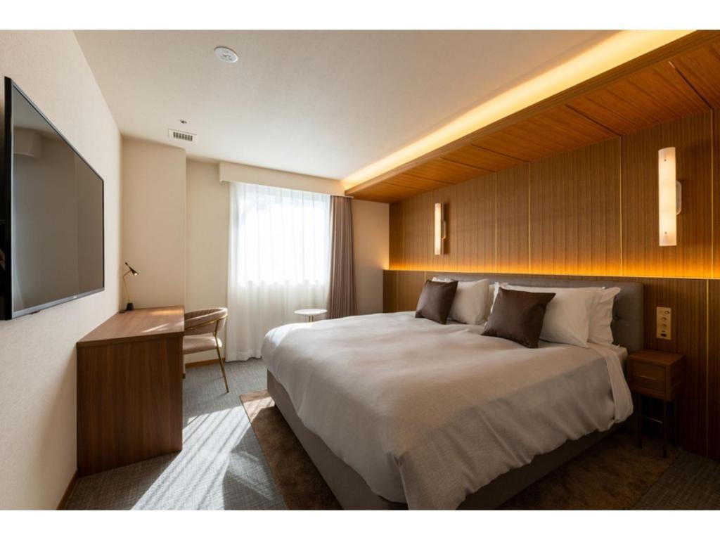 福岡市にあるThe OneFive Terrace Fukuoka - Vacation STAY 33419vの大型ベッドとテレビが備わるホテルルームです。