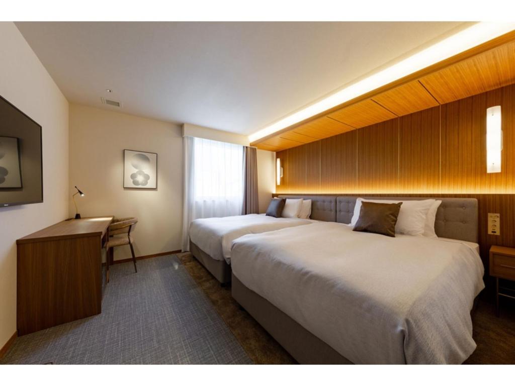 een hotelkamer met 2 bedden en een bureau bij The OneFive Terrace Fukuoka - Vacation STAY 33431v in Fukuoka