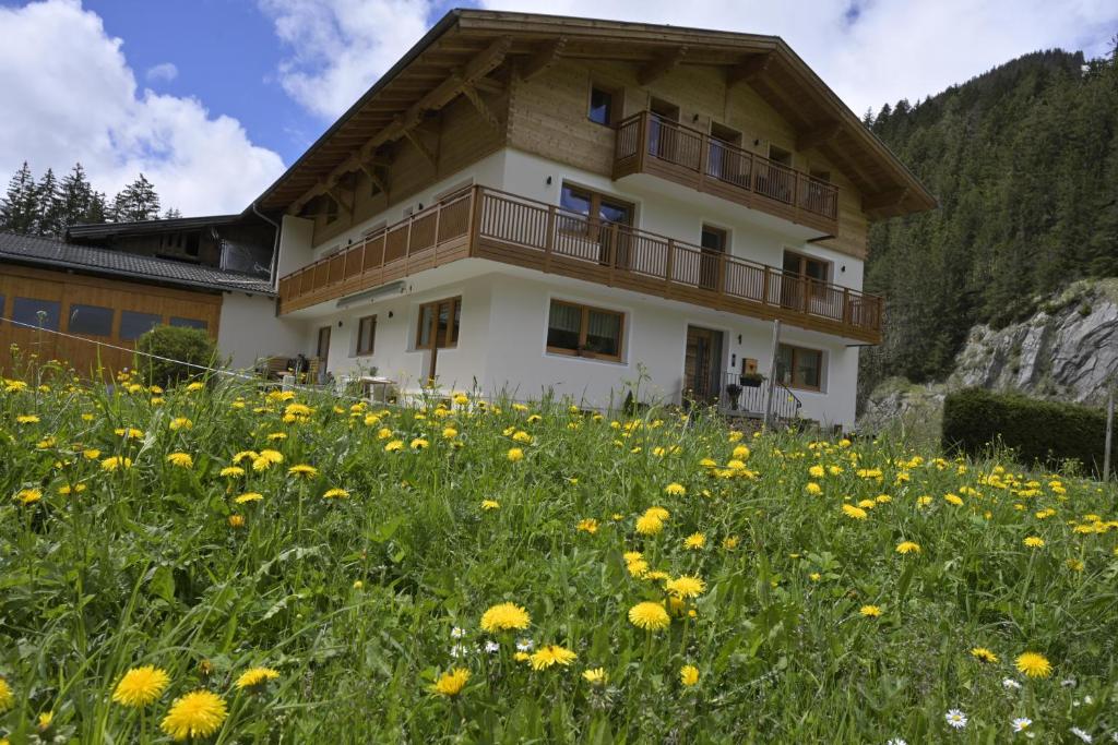 une maison sur une colline avec un champ de fleurs dans l'établissement Lechtal-Pur-Aparts, à Holzgau