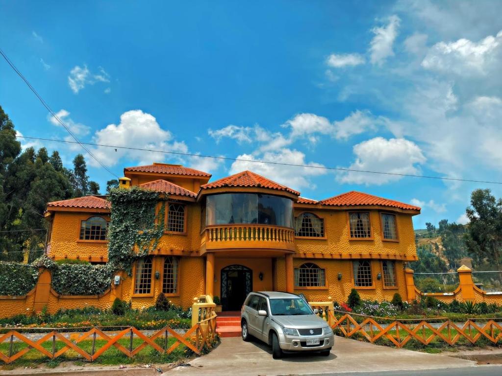 una casa amarilla con un coche aparcado delante de ella en Dream Garden Mountain Hotel, en San Juan