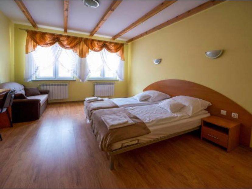 Pokoje Gościnne Barbara Wacławska في ايوافا: غرفة نوم بسرير كبير وأريكة