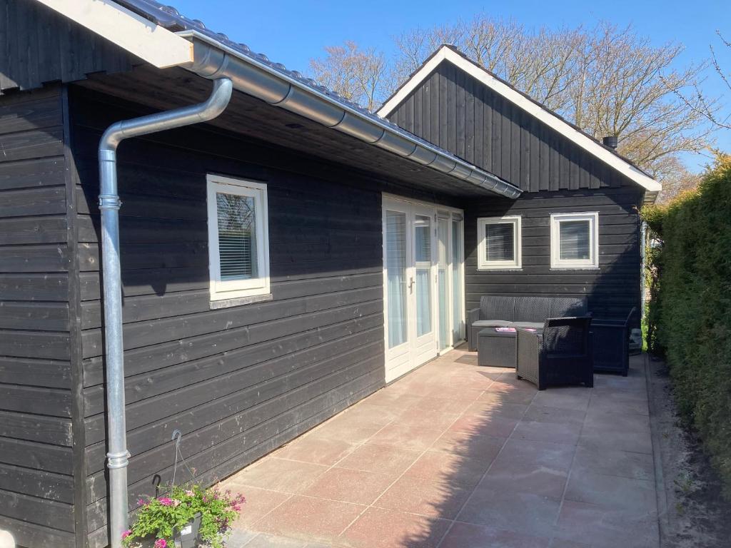 a black house with a porch and a patio at Vakantiehuis 't Laaisterplakky zonder drempels in Oude Bildtzijl