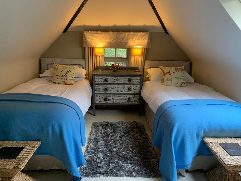two beds in a attic room with a window at Bootmenders B&B in Petersfield