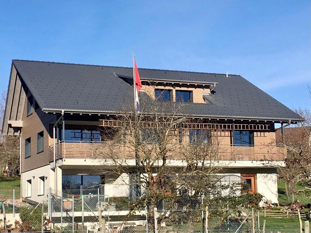 ein Haus mit einem schwarzen Dach und einer roten Flagge in der Unterkunft Naturnoech in Unterägeri