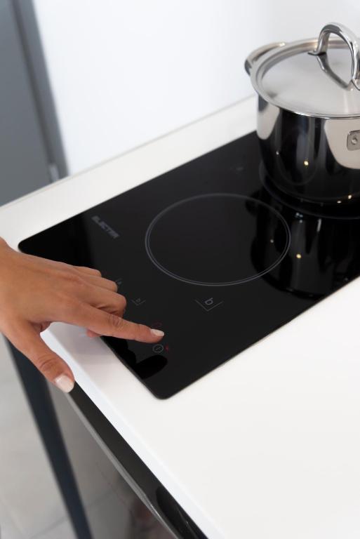 a hand on a stove with a pot on it at Seaside Suites in Kavos