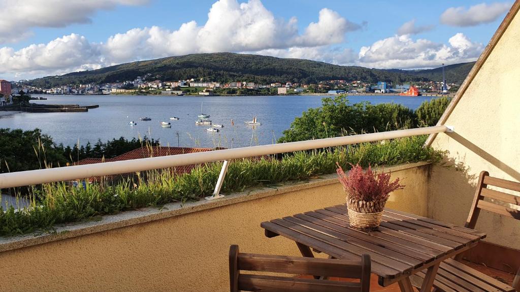 - une table en bois sur un balcon avec vue sur le lac dans l'établissement Apartamento nuevo a pie de playa, à Corcubión