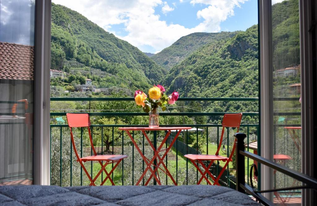 a table with a vase of flowers on a balcony with mountains at Agriturismo Conca Sandra - Farm Stay on Lake Como in Perledo