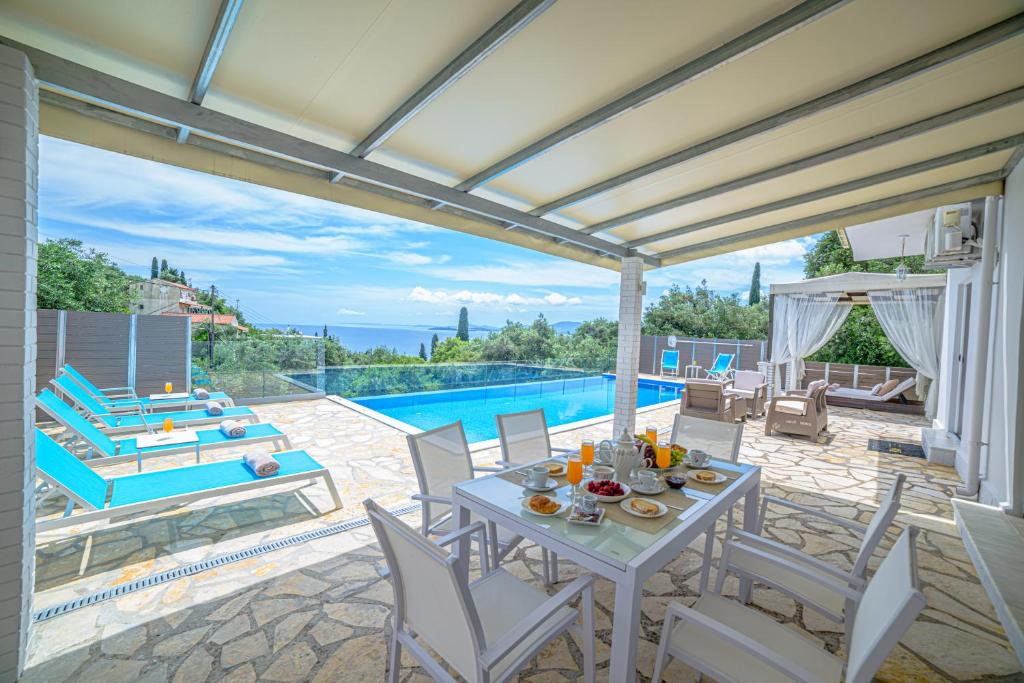 um pátio com uma mesa e cadeiras e uma piscina em Villa Hera-The infinity blue em Nisakion