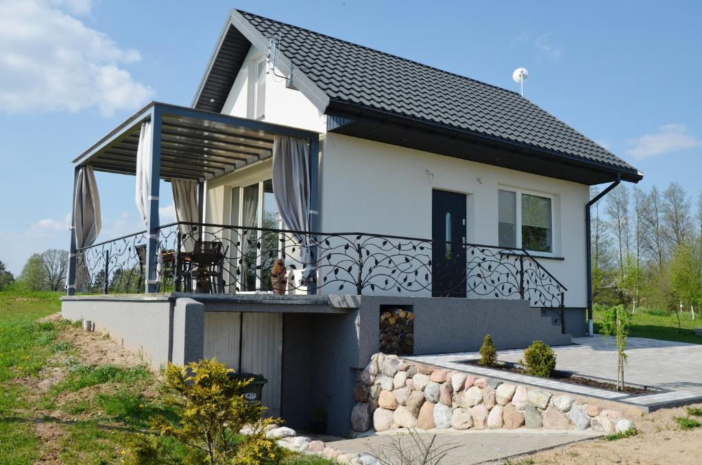 ein weißes Haus mit schwarzem Dach in der Unterkunft Domki na Wzgórzu - Rospuda in Filipów