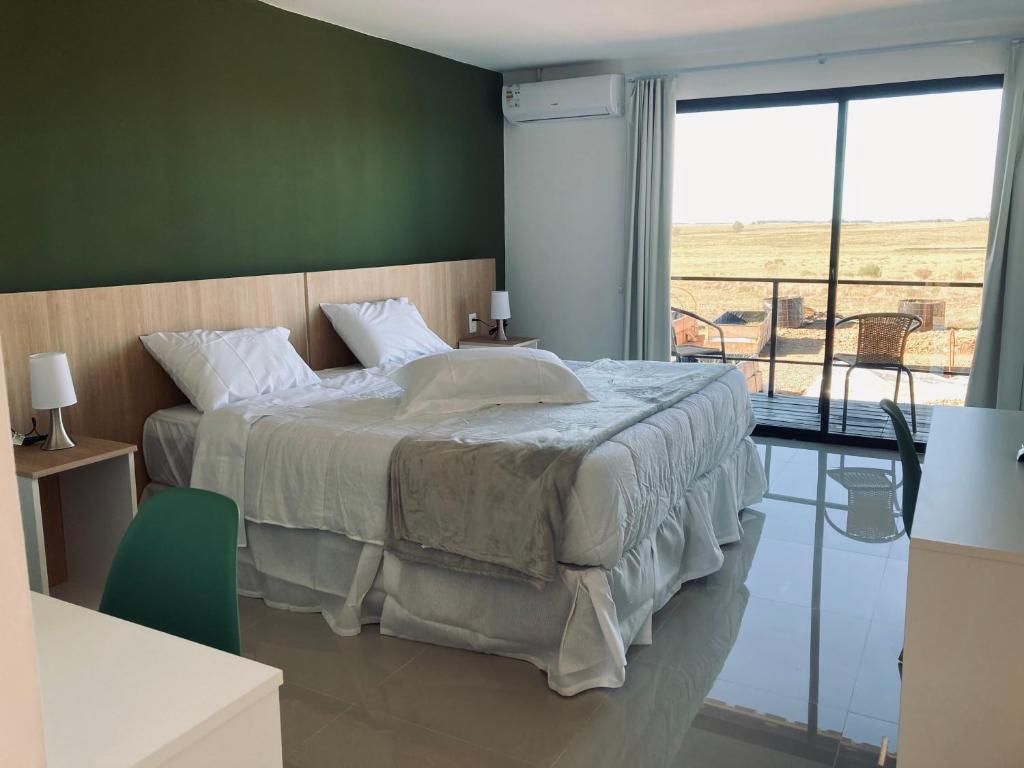 ein Schlafzimmer mit einem großen Bett und einem großen Fenster in der Unterkunft PLC Hotel Centenario in Paso de los Toros