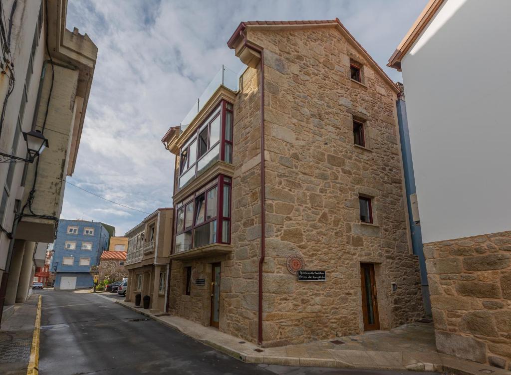an old stone building on the side of a street at Apartamentos Praia do Capitàn in Muxia