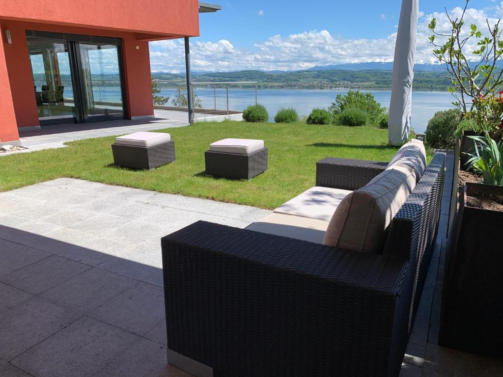 a couch sitting on a patio with a view of the water at Villa au bord du lac de Morat avec vue imprenable in Bellerive