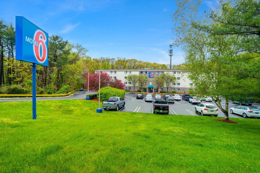 un panneau dans l'herbe à côté d'un parking dans l'établissement Motel 6-Milford, CT, à Milford