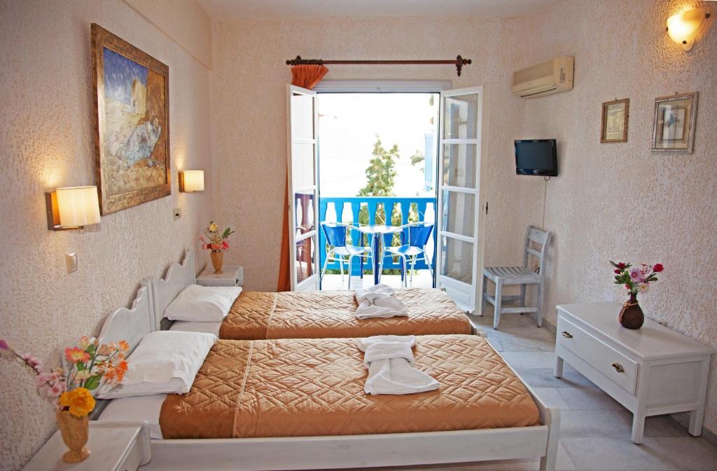 a hotel room with two beds and a balcony at St.George Valsamitis in Katapola