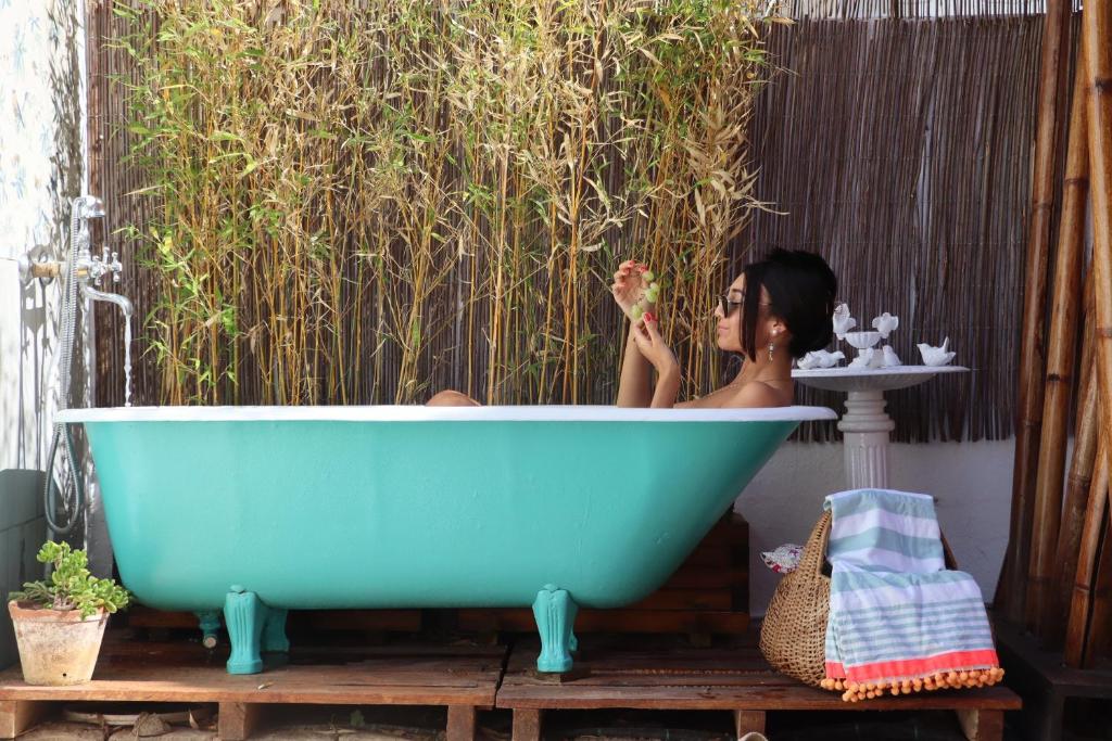 4 Cantos في فارو: امرأة تجلس في حوض الاستحمام الأزرق أمام الأدغال