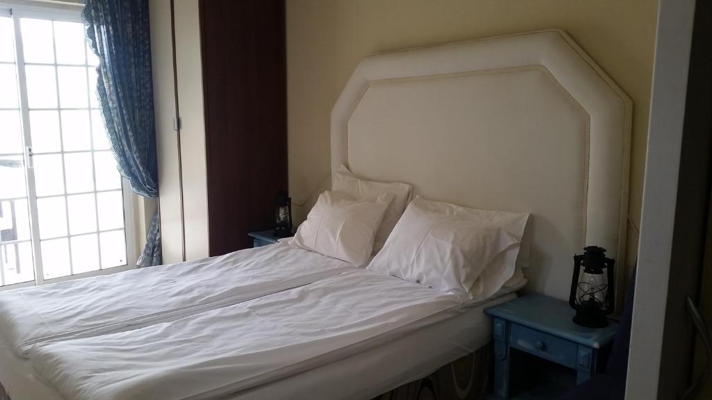 uma cama com lençóis brancos e almofadas ao lado de uma janela em Sara & Dany em Sintra