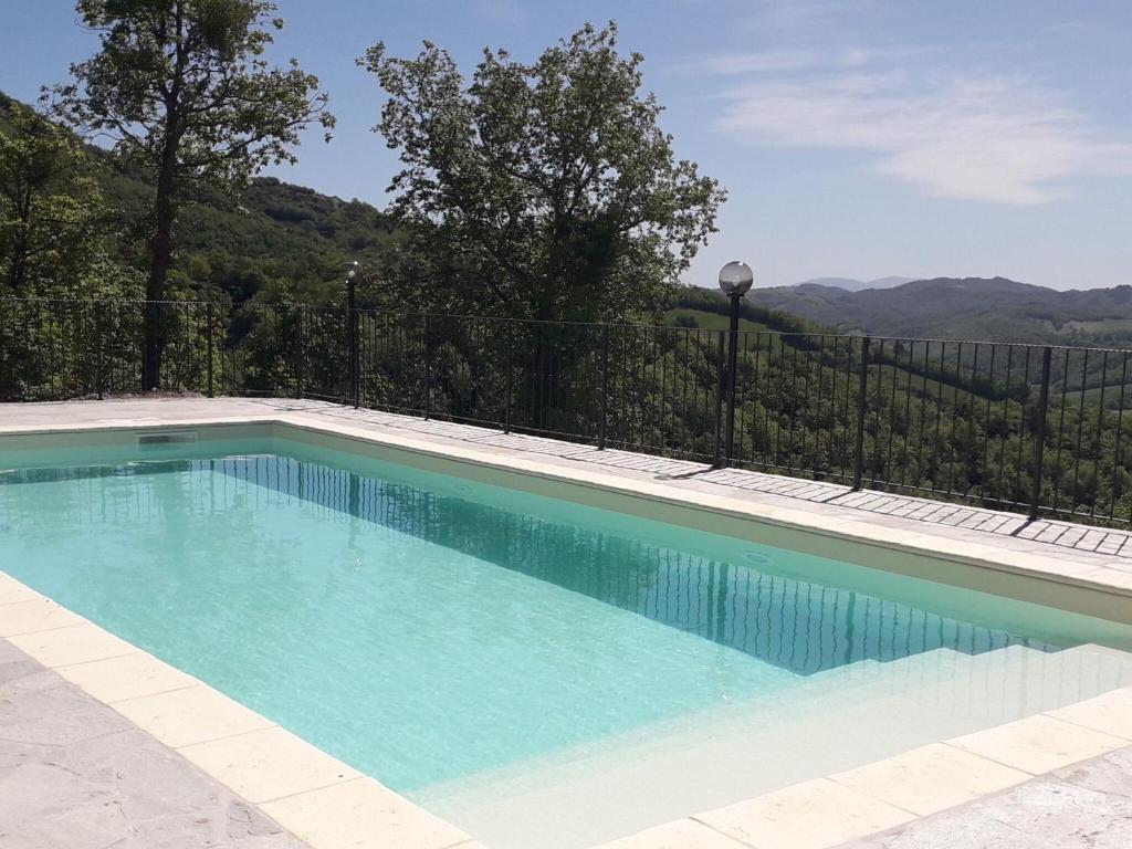 einen Pool mit blauem Wasser und einem Zaun in der Unterkunft Belvilla by OYO Poggio Marino in Carpegna