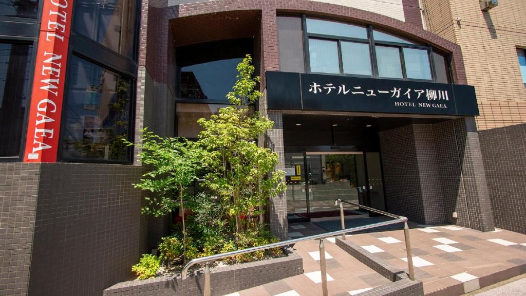 um edifício com uma árvore em frente em Hotel New Gaea Yanagawa em Yanagawa