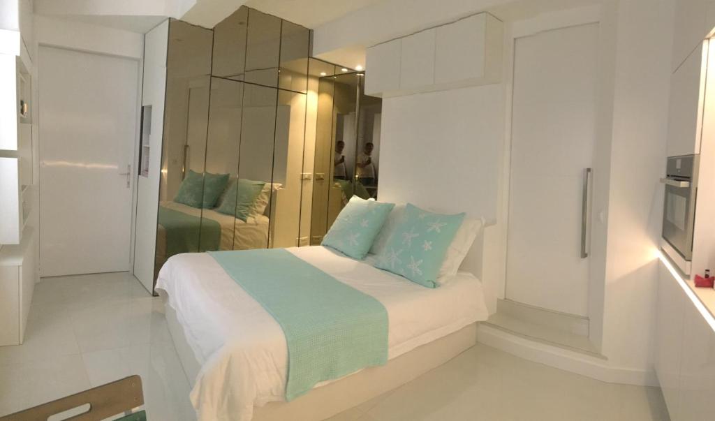 una camera bianca con letto e cuscini blu di Stone studio a Saint-Tropez