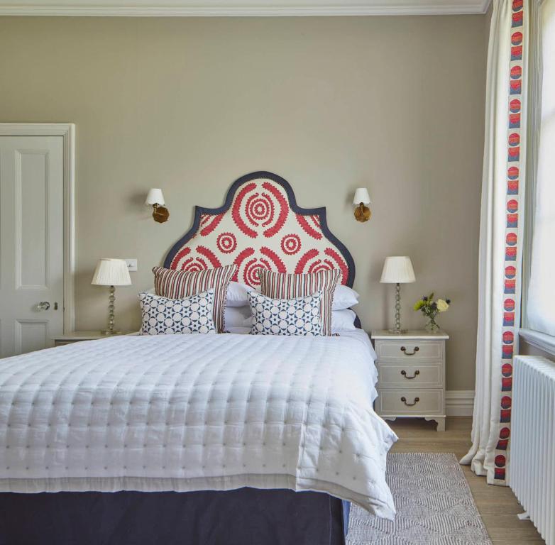 a bedroom with a large bed with a red and white headboard at Cockloft Romantic Countryside Hideaway in Bishops Cannings