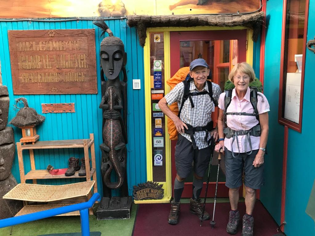 Ein Mann und eine Frau stehen vor einem Gebäude in der Unterkunft Global Village Travellers Lodge in Greymouth