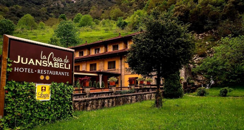 een bord voor een gebouw in een veld bij Logis Hotel Restaurante La Casa de Juansabeli in Arenas de Cabrales