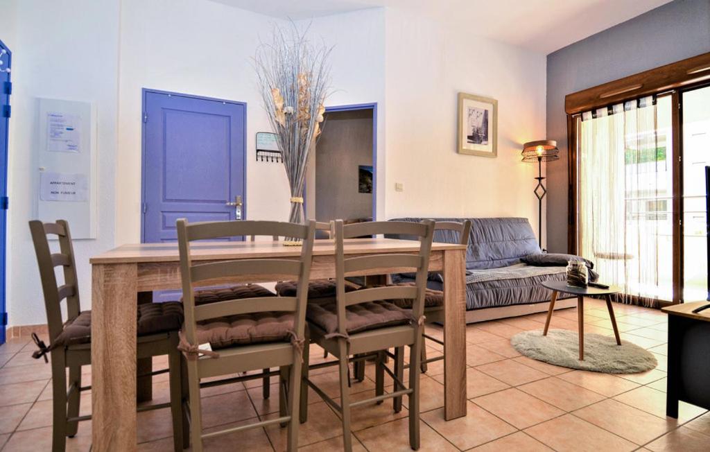 a dining room with a table and chairs and a couch at appartement 3 min a pied du centre d'Uzès parking piscine in Uzès
