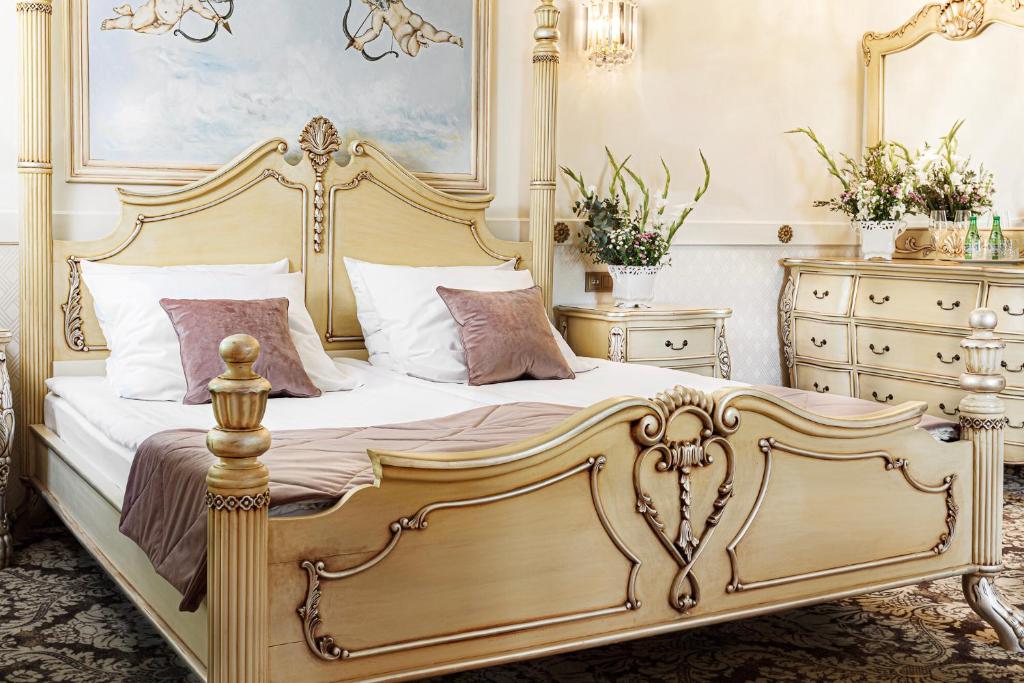 Ornately carved wooden bed footboard with decorative detailing and plush pillows on bed.