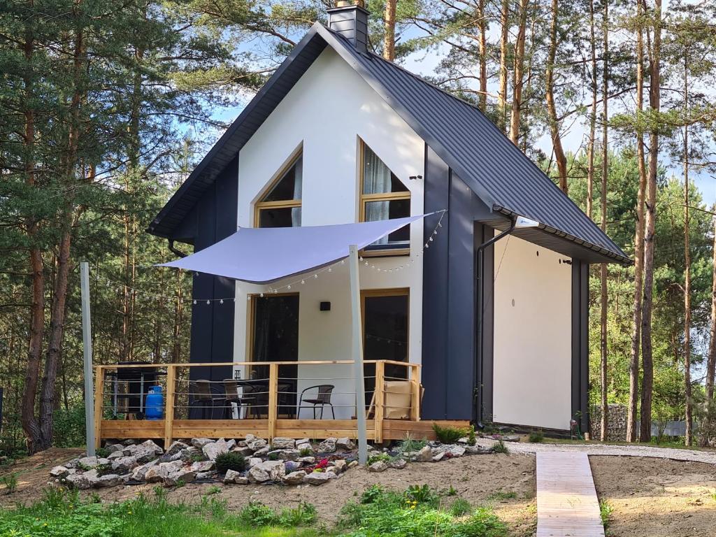 a tiny house in the woods with a black roof at Na Hamaku Jacuzzi & Sauna in Marzysz