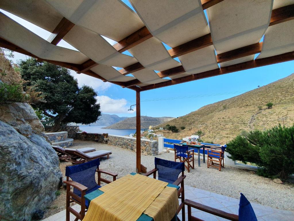 un patio con mesa y sillas bajo una sombrilla de madera en Villa Orea Thea, Emborios, Kalymnos en Emborios