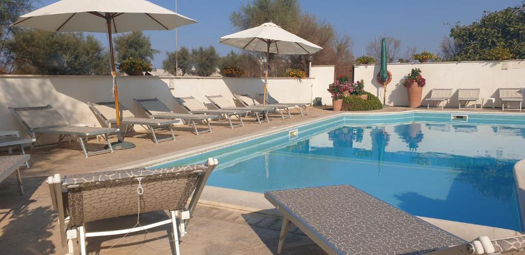 basen z leżakami i parasolami obok niego w obiekcie Hotel Corallo w mieście Fregene
