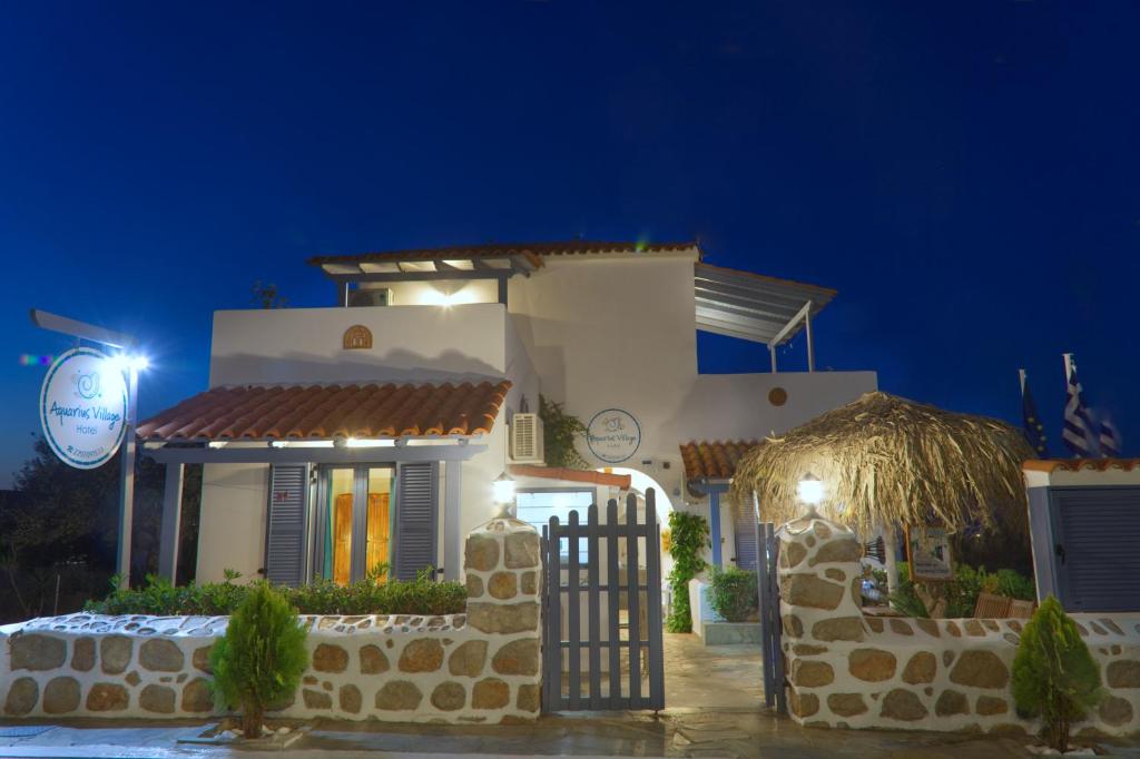 a white house with a gate at night at Aquarius Village Agistri in Skala