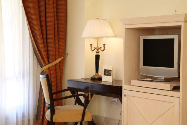 Habitación de hotel con escritorio, TV y lámpara. en Hotel Lido degli Scogli en Crotone