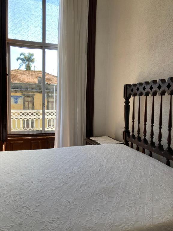 a bedroom with a bed and a large window at Hospedaria Boavista in Porto