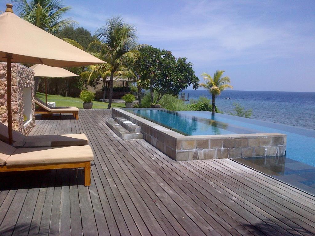a swimming pool on a wooden deck next to the ocean at Villa Bukit Segara in Amed