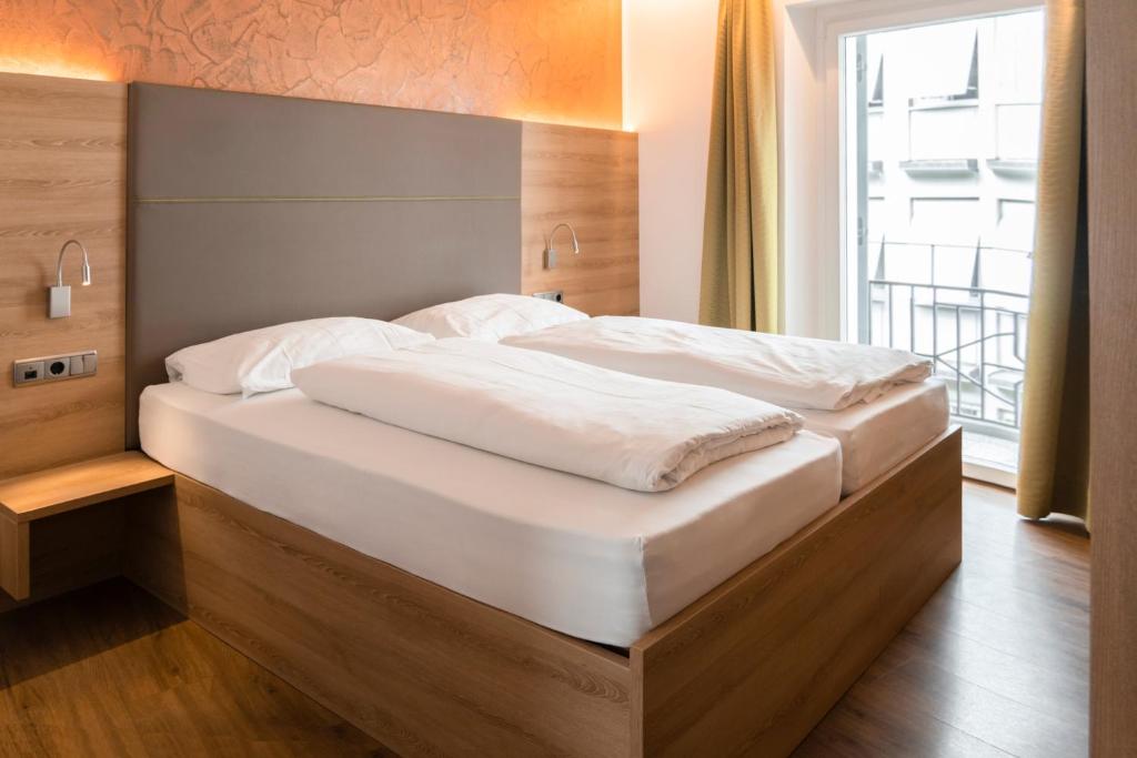 a large bed in a room with a large window at Feichter Hotel & Bistro in Bolzano