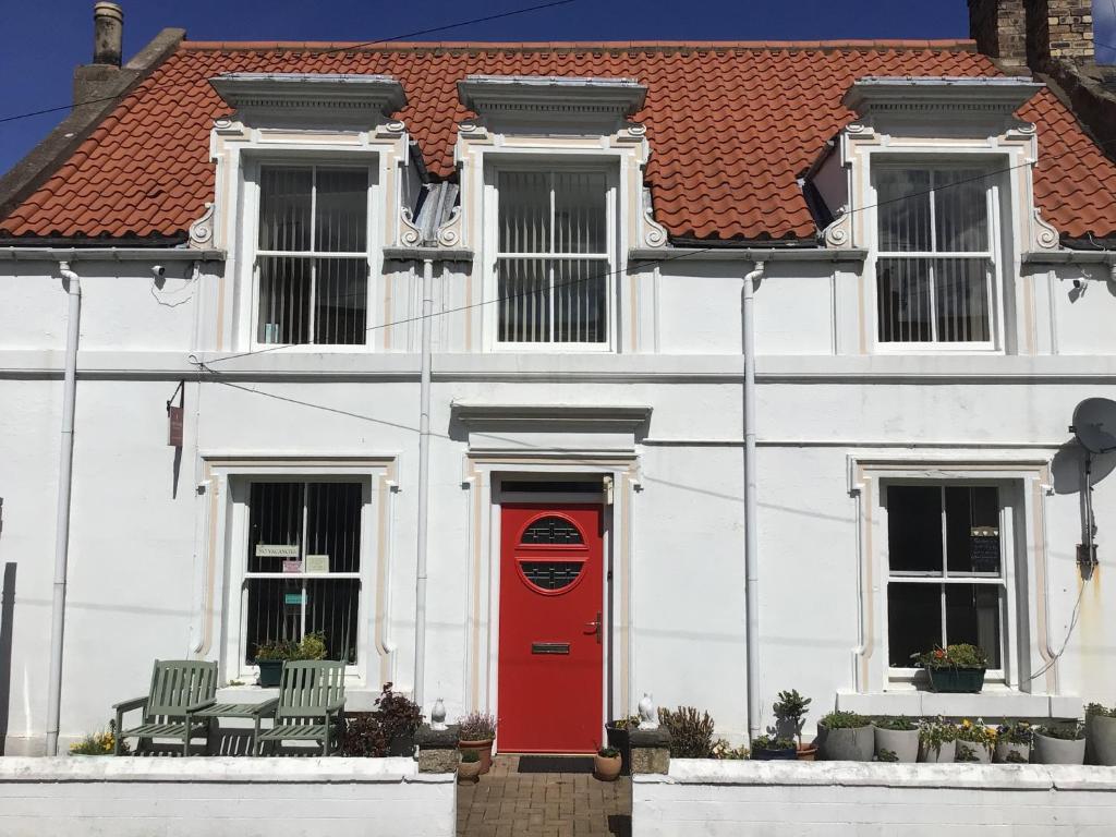 a white house with a red door and two chairs at Abbotsford B&B in Norham