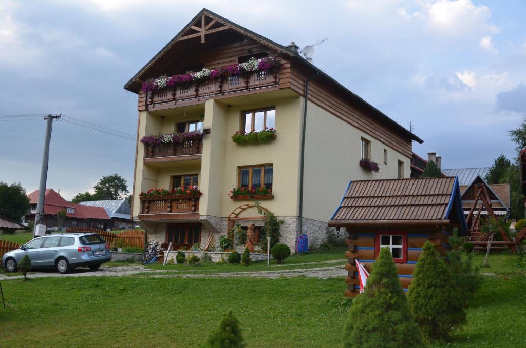 a house with a balcony and a car parked in front of it at Privát Domino in Ždiar