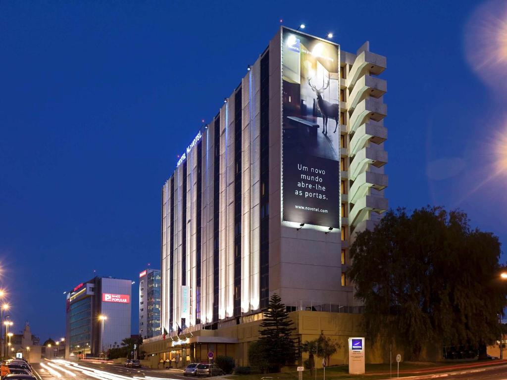 ein hohes Gebäude mit einem Schild an der Seite in der Unterkunft Novotel Lisboa in Lissabon