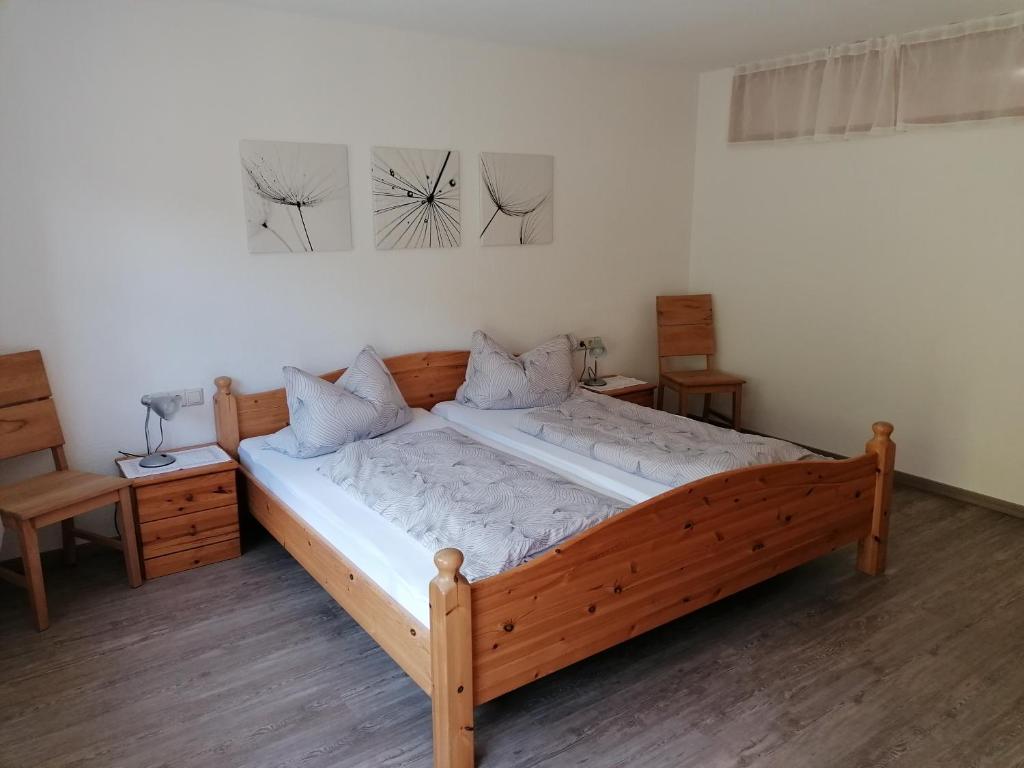 Achbergにある70m²- Ferienwohnung mit Terrasseの木製のベッドフレームが備わるドミトリールームのベッド1台分です。