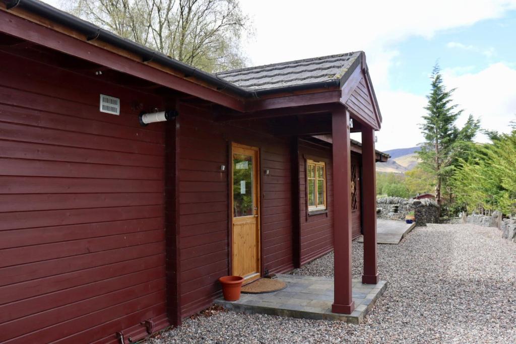 czerwony budynek z drzwiami i werandą w obiekcie Lodge 38 Rowardennan , Loch Lomond w Glasgow