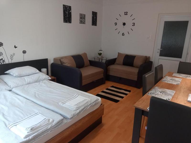 a bedroom with a bed and a couch and a table at merRelax Apartman in Miskolc