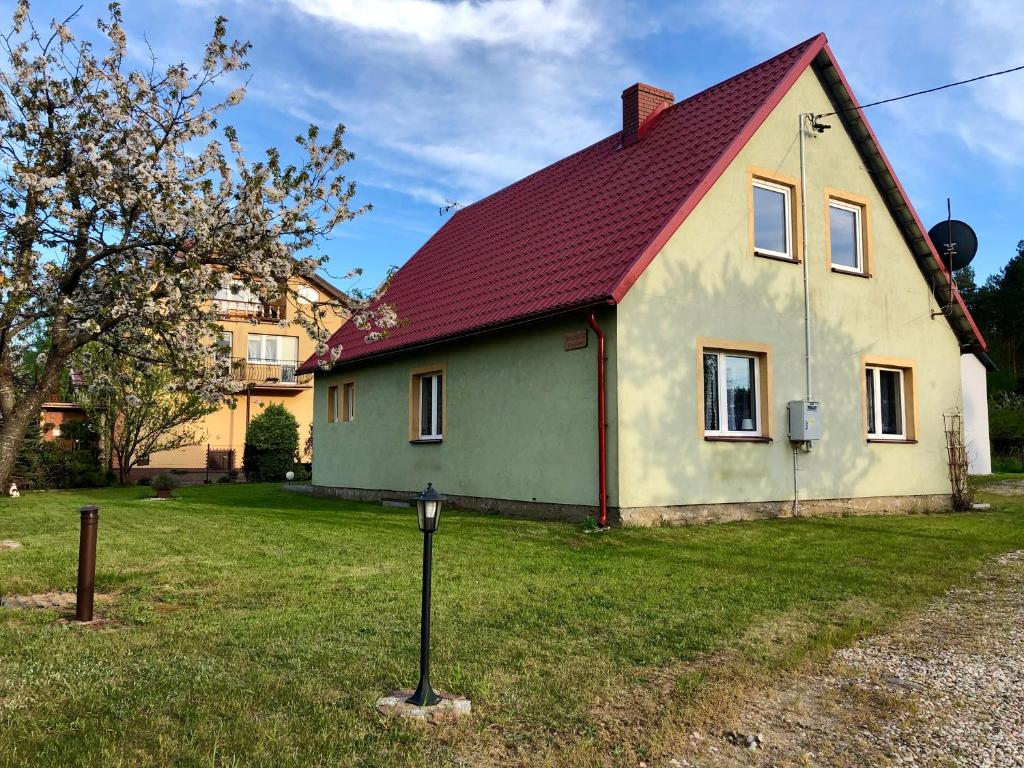 a house with a red roof in the grass at Przystań Rodzinna in Kopalino