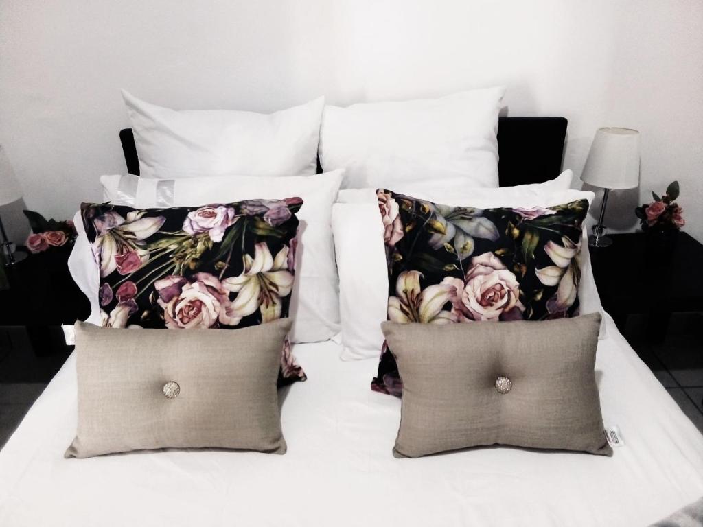 duas almofadas numa cama com flores em The Cottage em Grahamstown