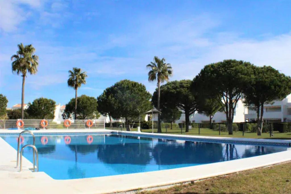 een zwembad met palmbomen op de achtergrond bij RETAMA GOLF Novo Sancti Petri in Chiclana de la Frontera